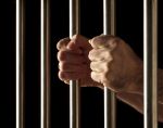 hands on jail bars on black background